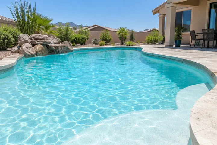 Smooth bright white plaster pool finish under clear shallow water giving a light turquoise color, sunny day